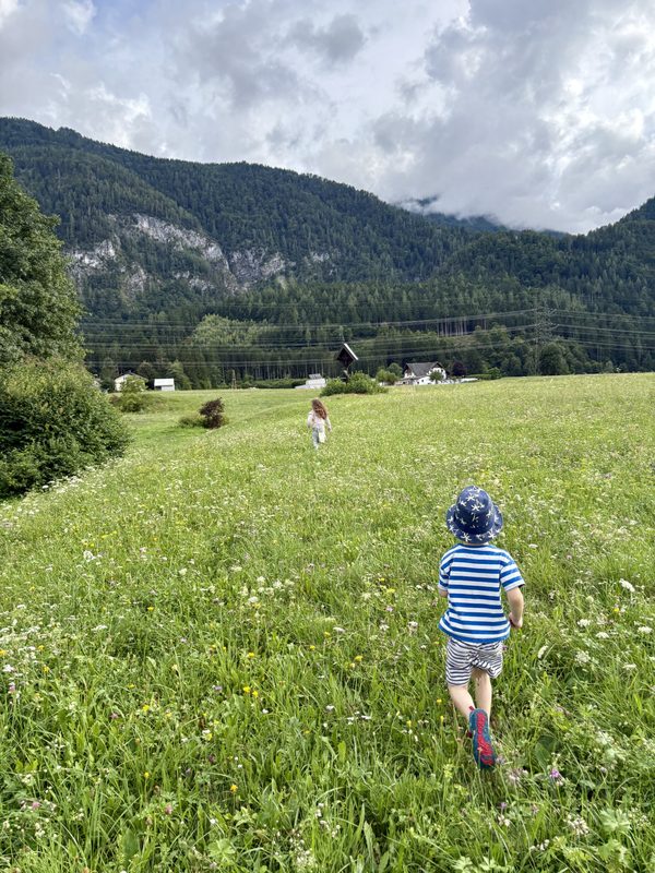Kinder spielen auf einer Wiese mit Bergblick